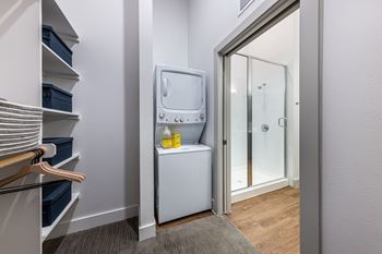 a small laundry room with a washer and dryer in it and a mirror at The Monroe Apartments, Austin, 78741